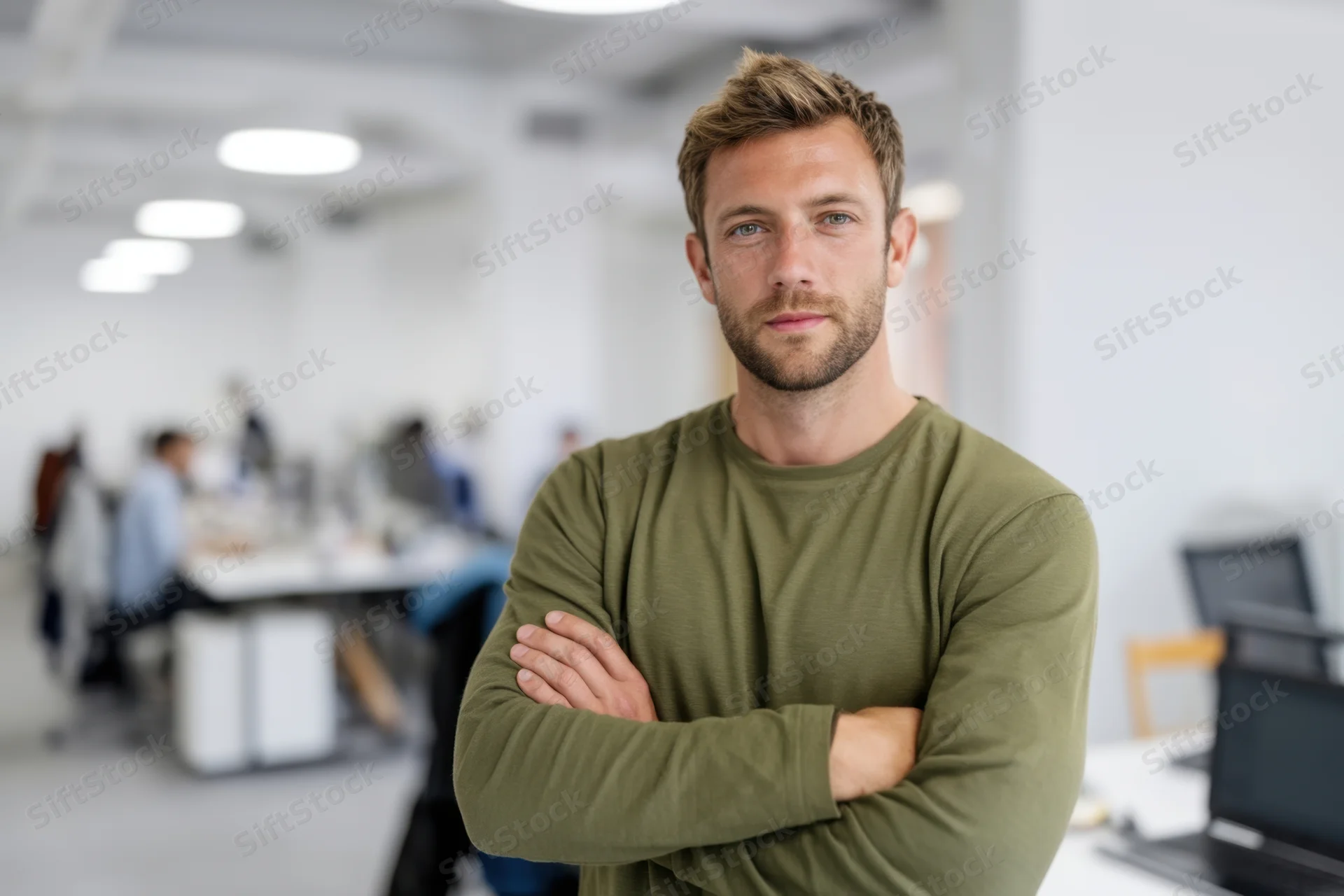 Man with arms crossed standing in office workspace