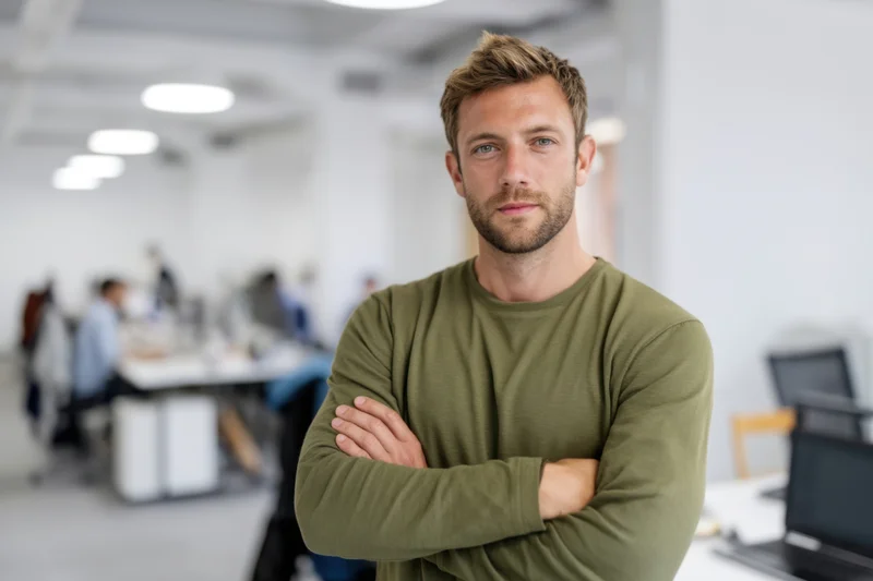 Man with arms crossed standing in office workspace