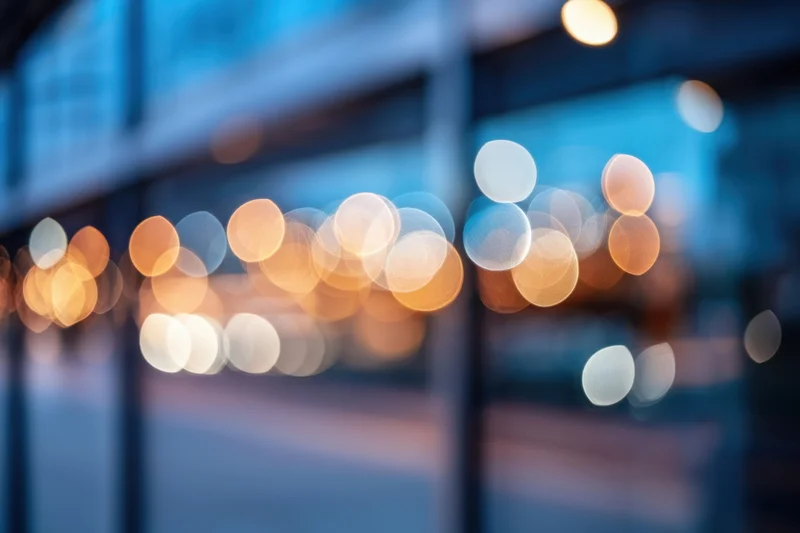 Blurred city lights with bokeh effect on glass storefronts at twilight