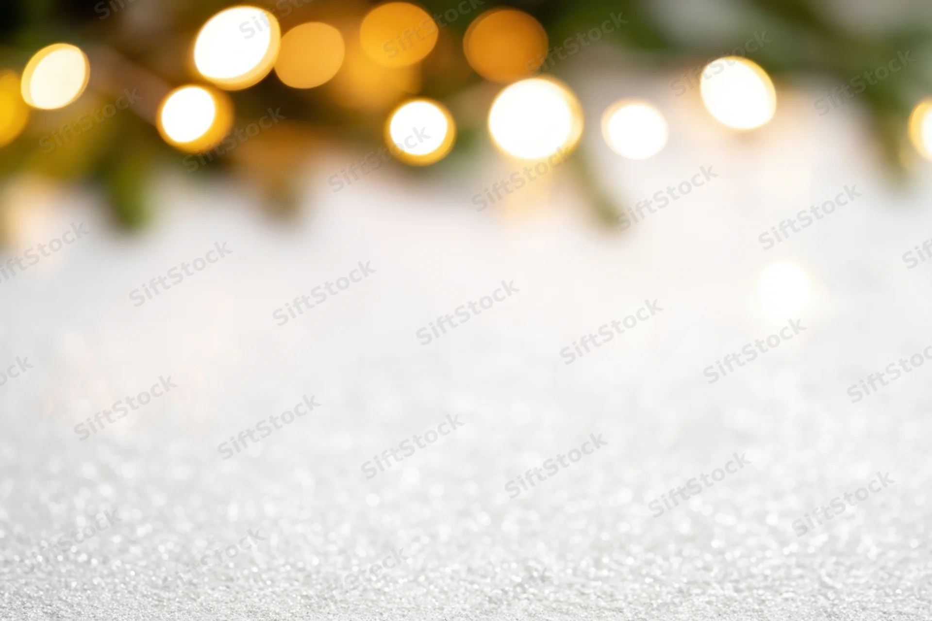Glittering white surface with blurred golden lights in the background for holiday decoration