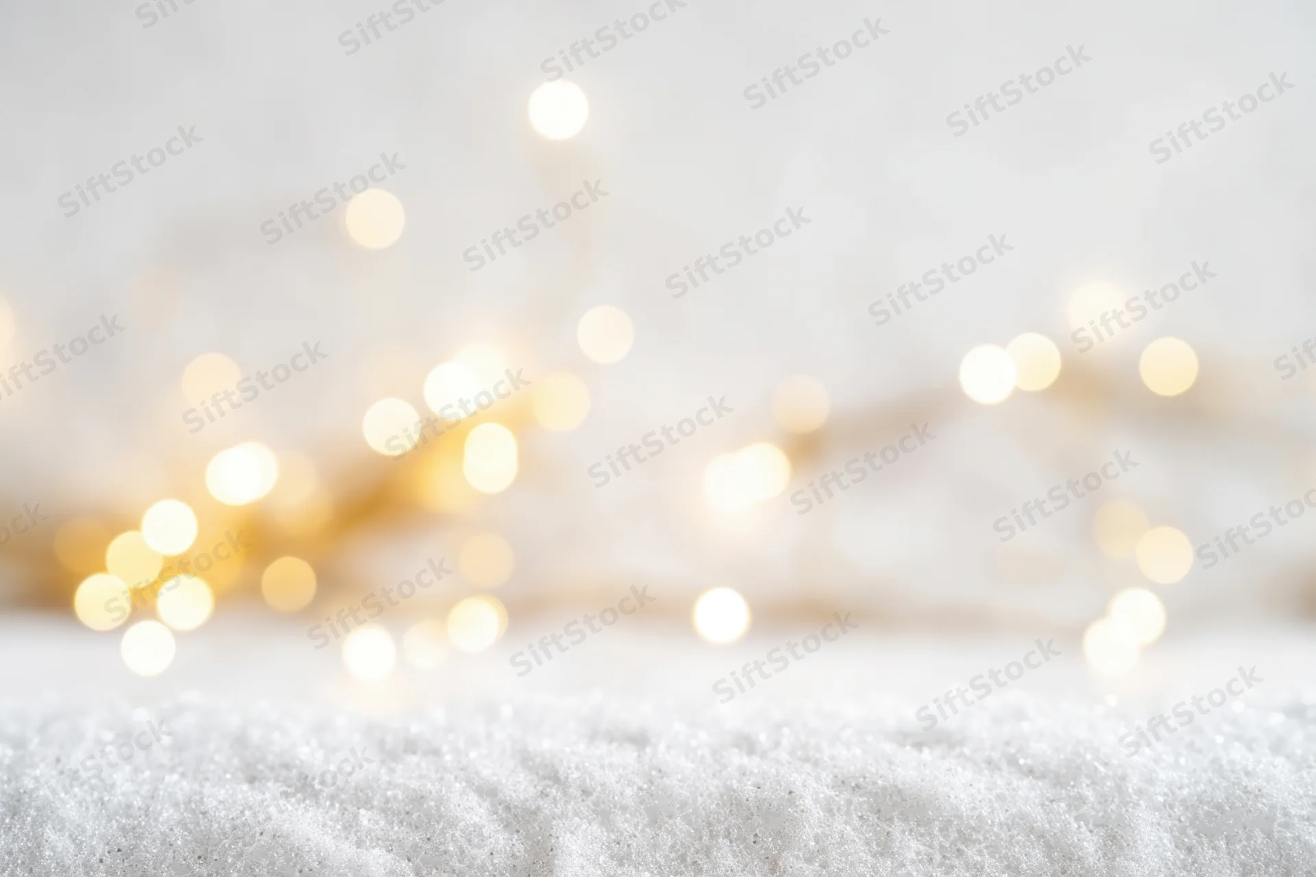 Soft-focused white snow surface with blurred golden lights in background