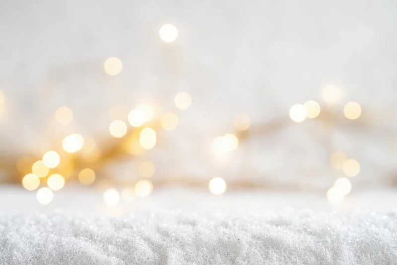 Soft-focused white snow surface with blurred golden lights in background