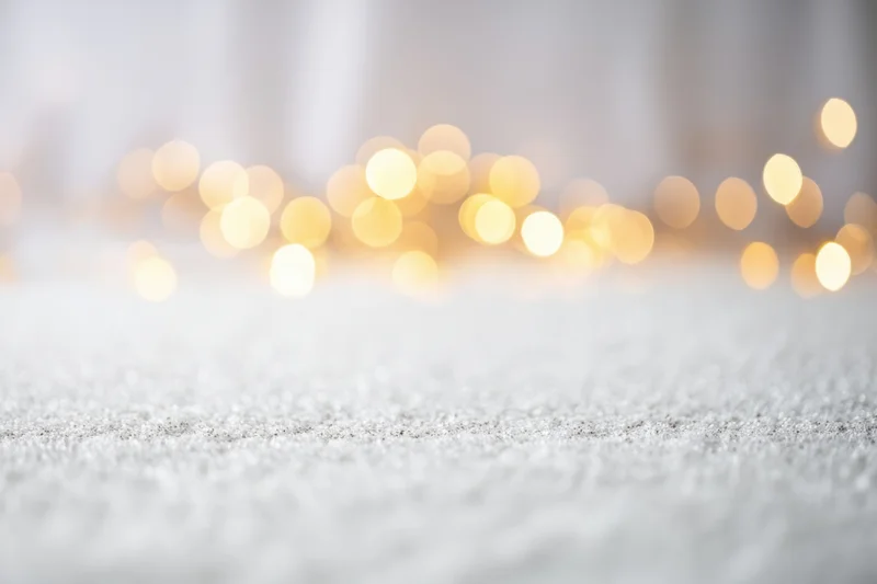 Glittering white surface with soft-focus warm bokeh lights in background