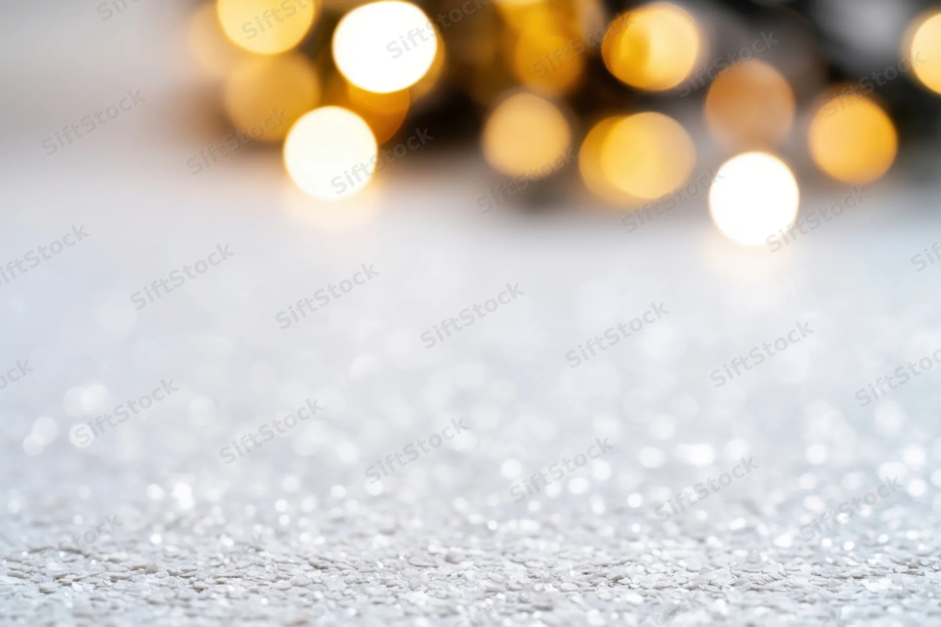 Glittering white textured surface with blurred golden lights in background