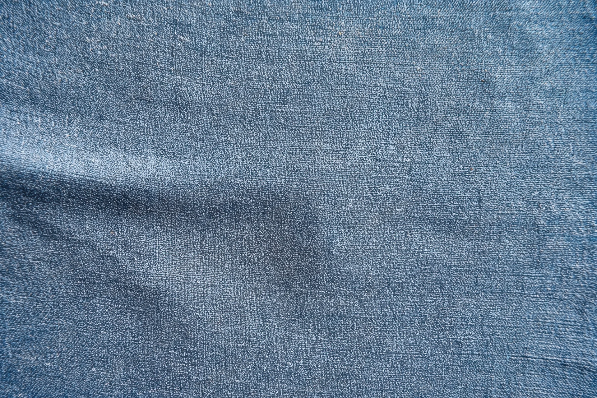 Close-up of blue-gray denim fabric texture with visible weave and slight folds