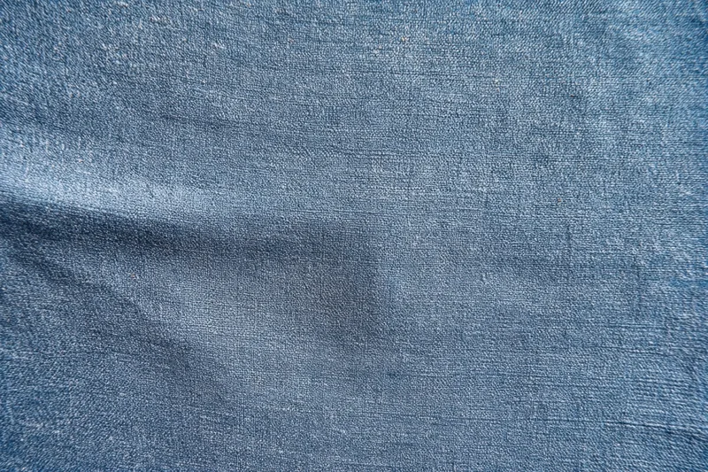 Close-up of blue-gray denim fabric texture with visible weave and slight folds