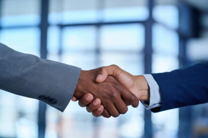 Close-up of two business professionals shaking hands in an office setting