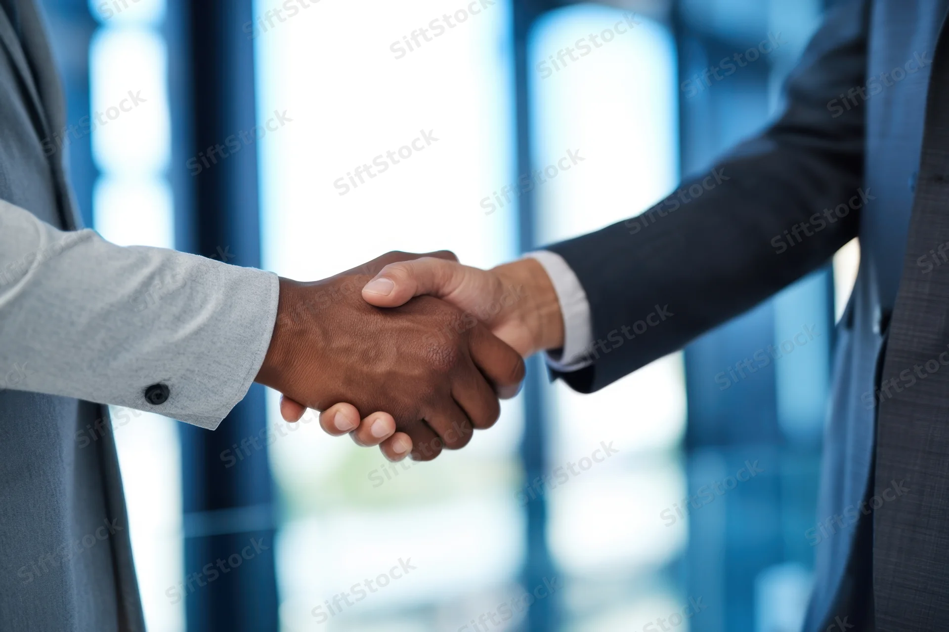 Close-up of two business professionals shaking hands in an office setting