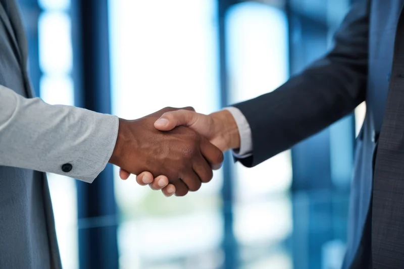 Close-up of two business professionals shaking hands in an office setting