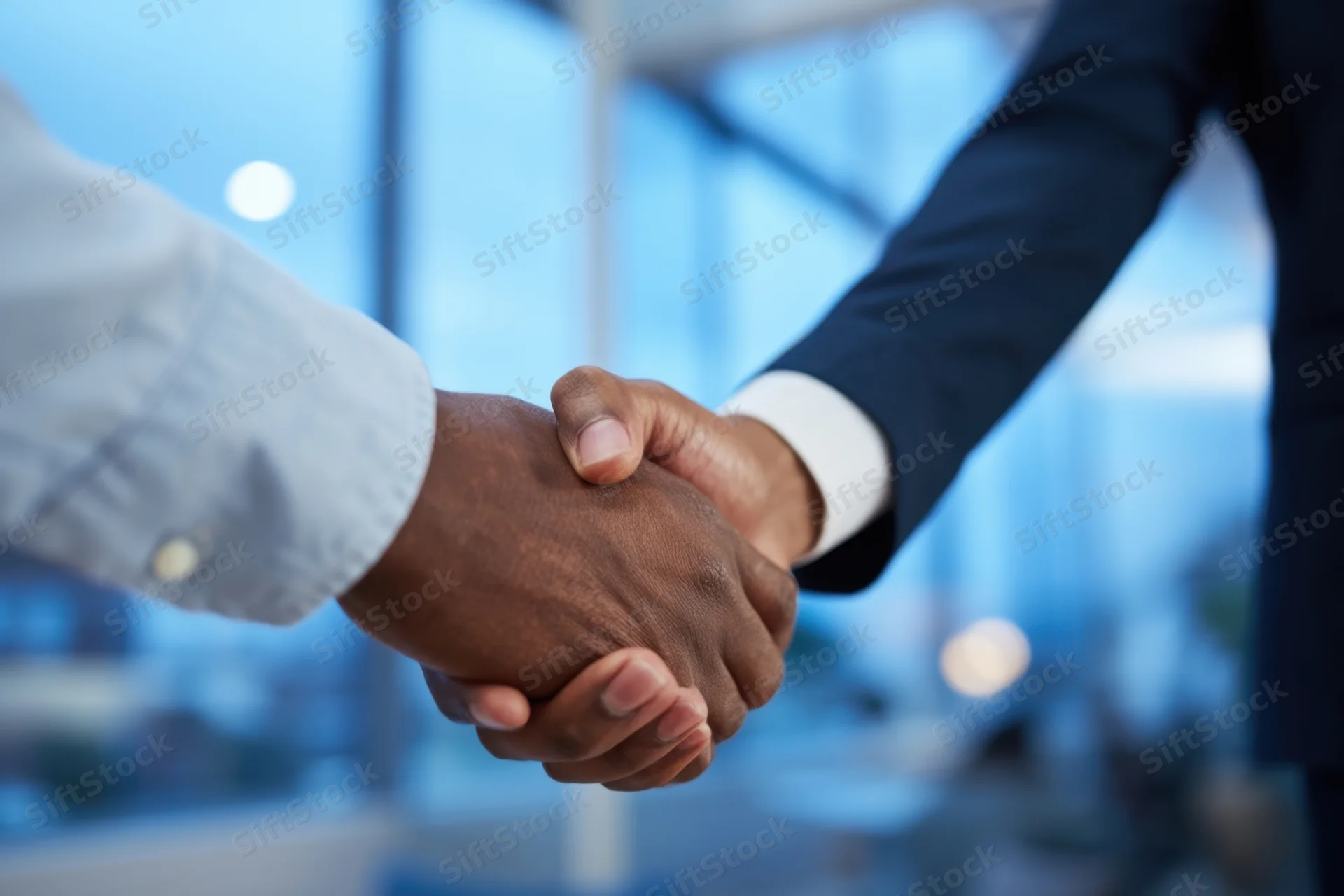 Close-up of two business professionals shaking hands in a modern office setting