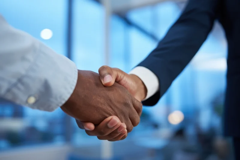 Close-up of two business professionals shaking hands in a modern office setting