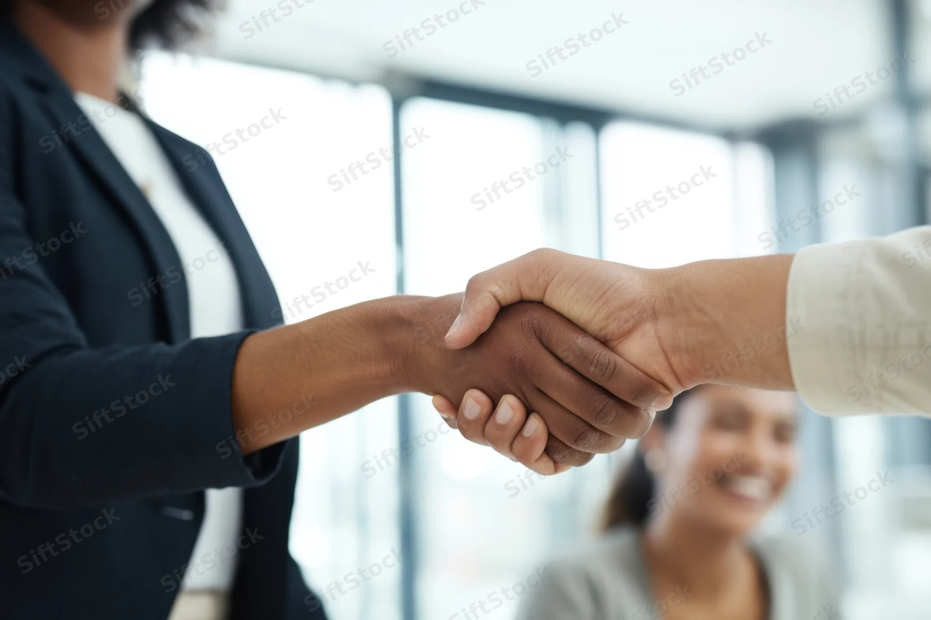 Two business professionals shaking hands in a bright office interior