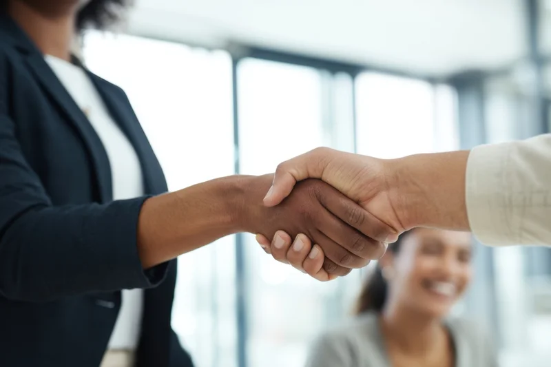 Two business professionals shaking hands in a bright office interior