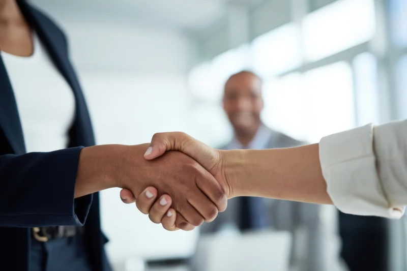 Two business professionals shaking hands in an office setting