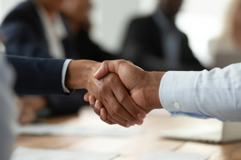 Two people shaking hands at a business meeting in an office setting