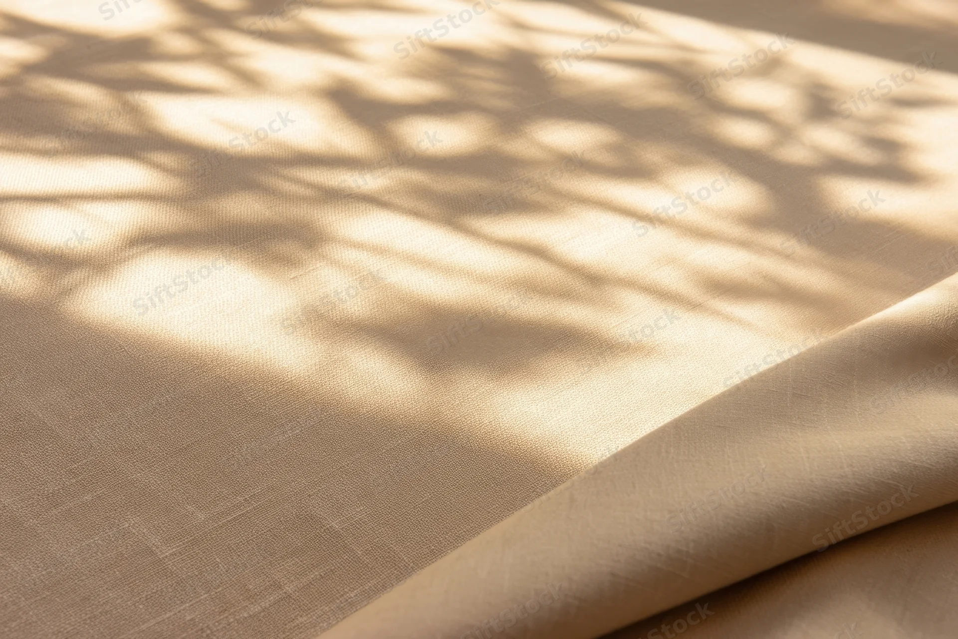 Beige fabric with dappled leaf shadows and soft folds, lit by natural sunlight