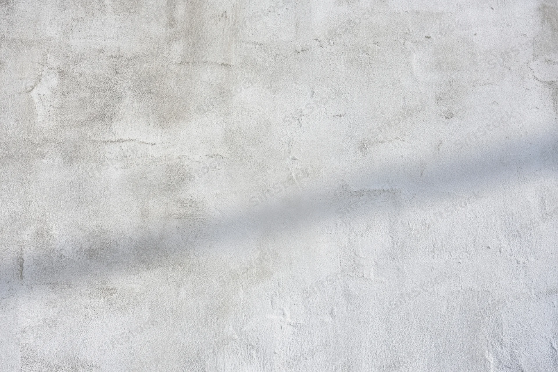 Weathered gray concrete wall with rough texture and shadowed surface