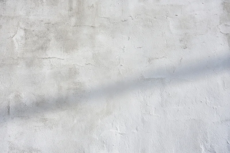 Weathered gray concrete wall with rough texture and shadowed surface