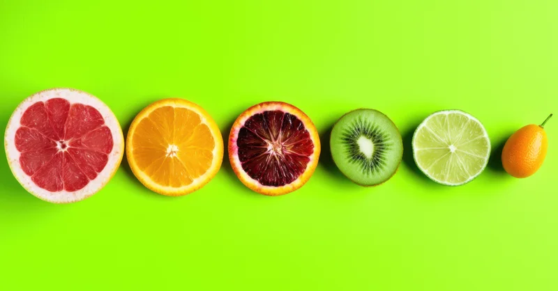Row of citrus fruit cross-sections arranged on a vivid green background