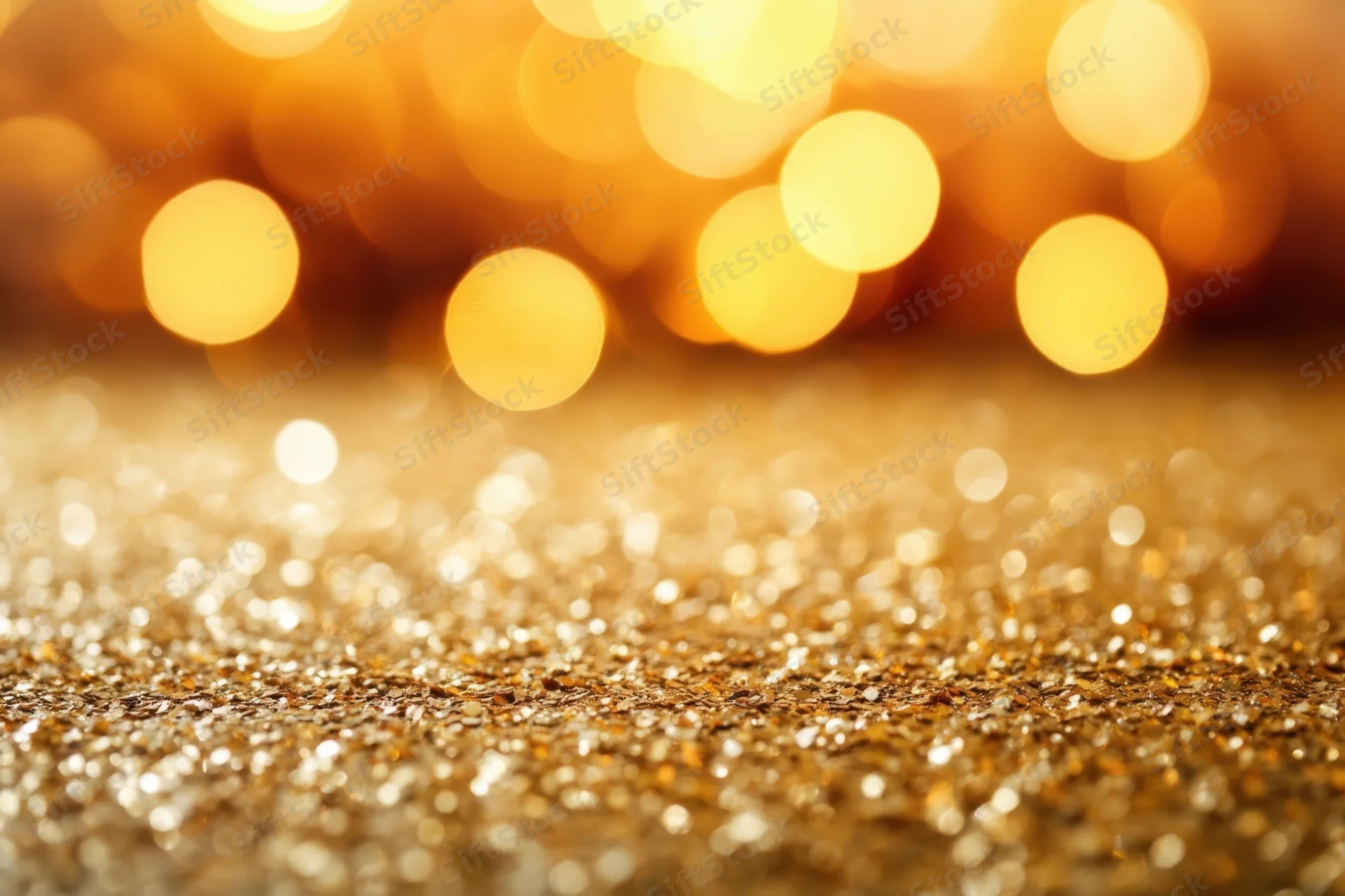 Shimmering golden glitter surface with soft bokeh lights in background