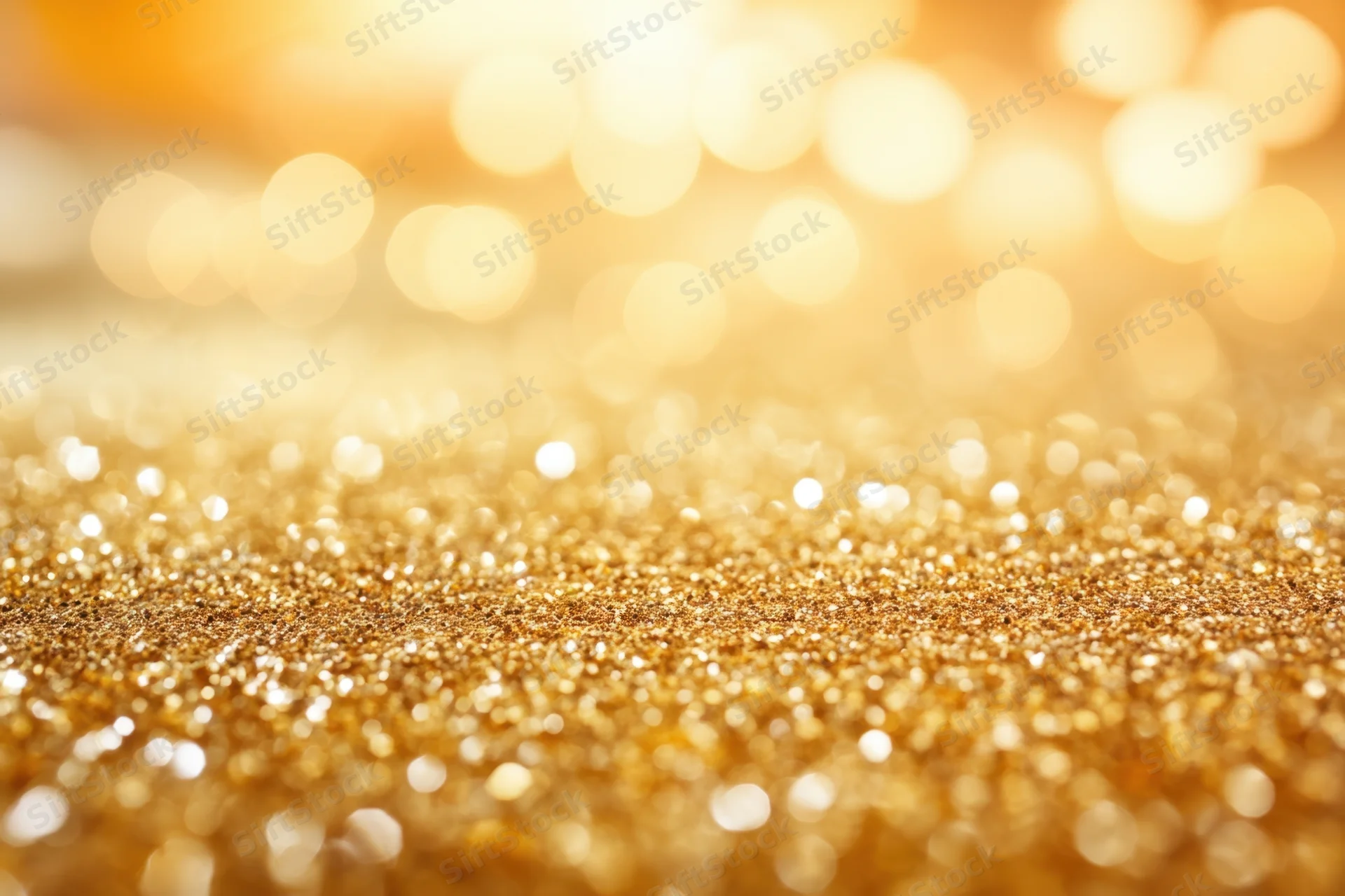Shimmering golden glitter surface with soft bokeh lights in the background