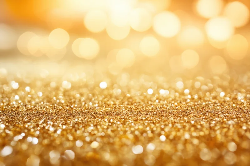 Shimmering golden glitter surface with soft bokeh lights in the background