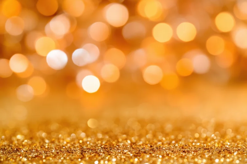 Shimmering golden glitter surface with soft bokeh lights in background