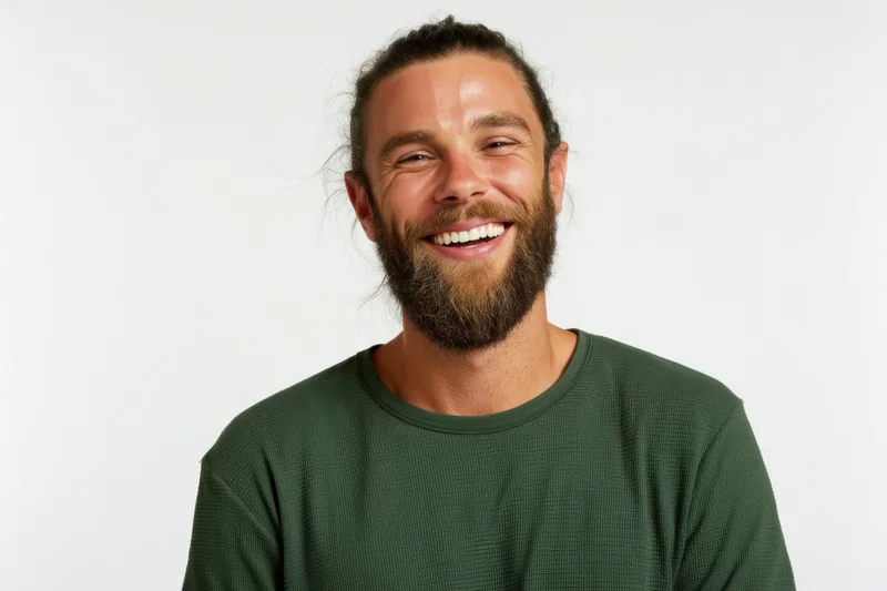 Smiling man with beard and hair tied back wearing green ribbed shirt in studio portrait