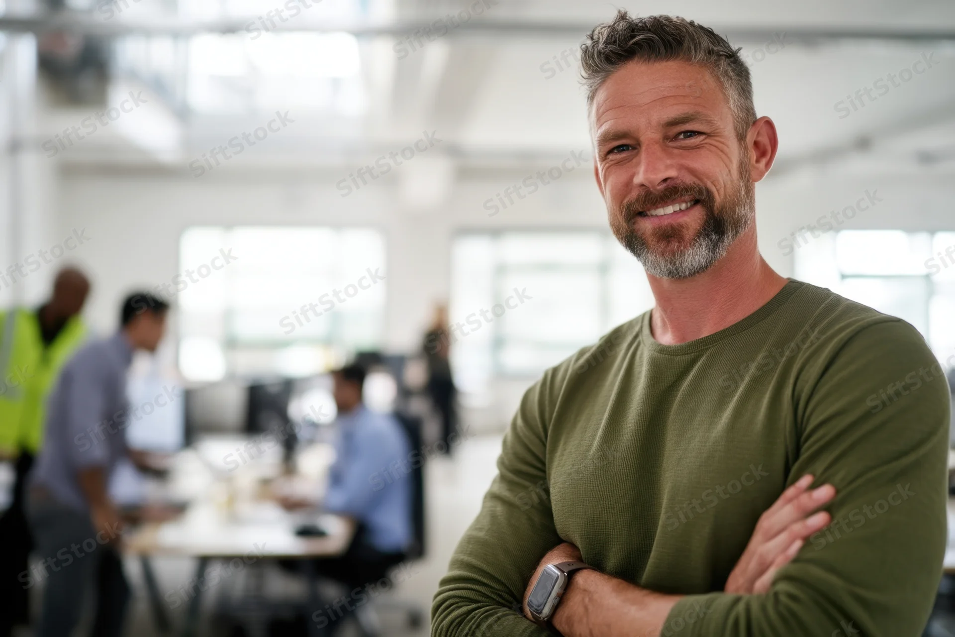 Smiling man with arms crossed in modern office workplace