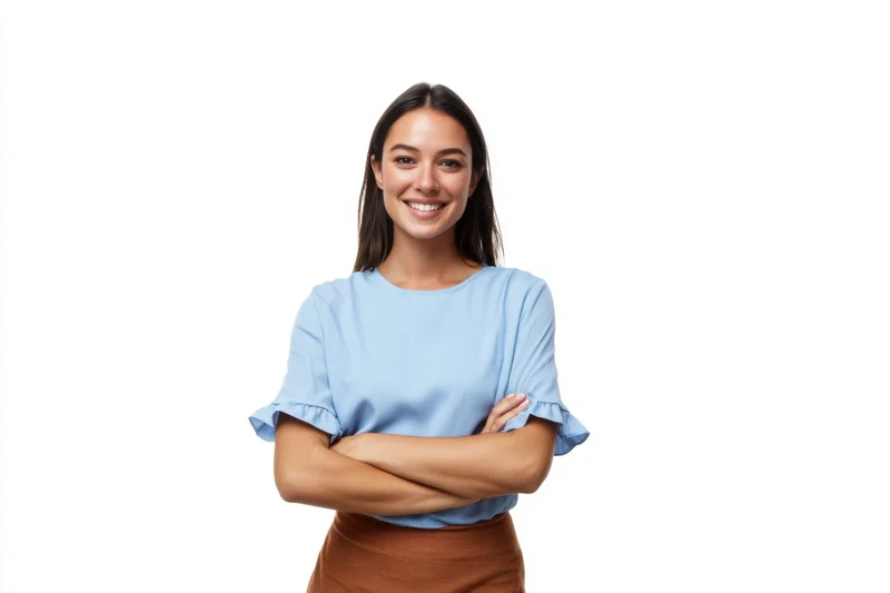 Smiling woman with arms crossed wearing a blue blouse and brown skirt against a white background