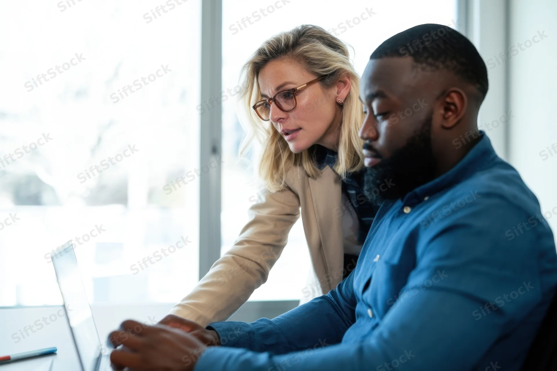 Two colleagues collaborating over a laptop in a bright office