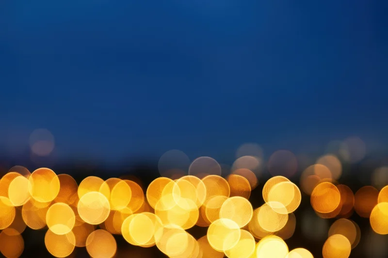 Warm golden bokeh lights scattered across a deep blue night sky