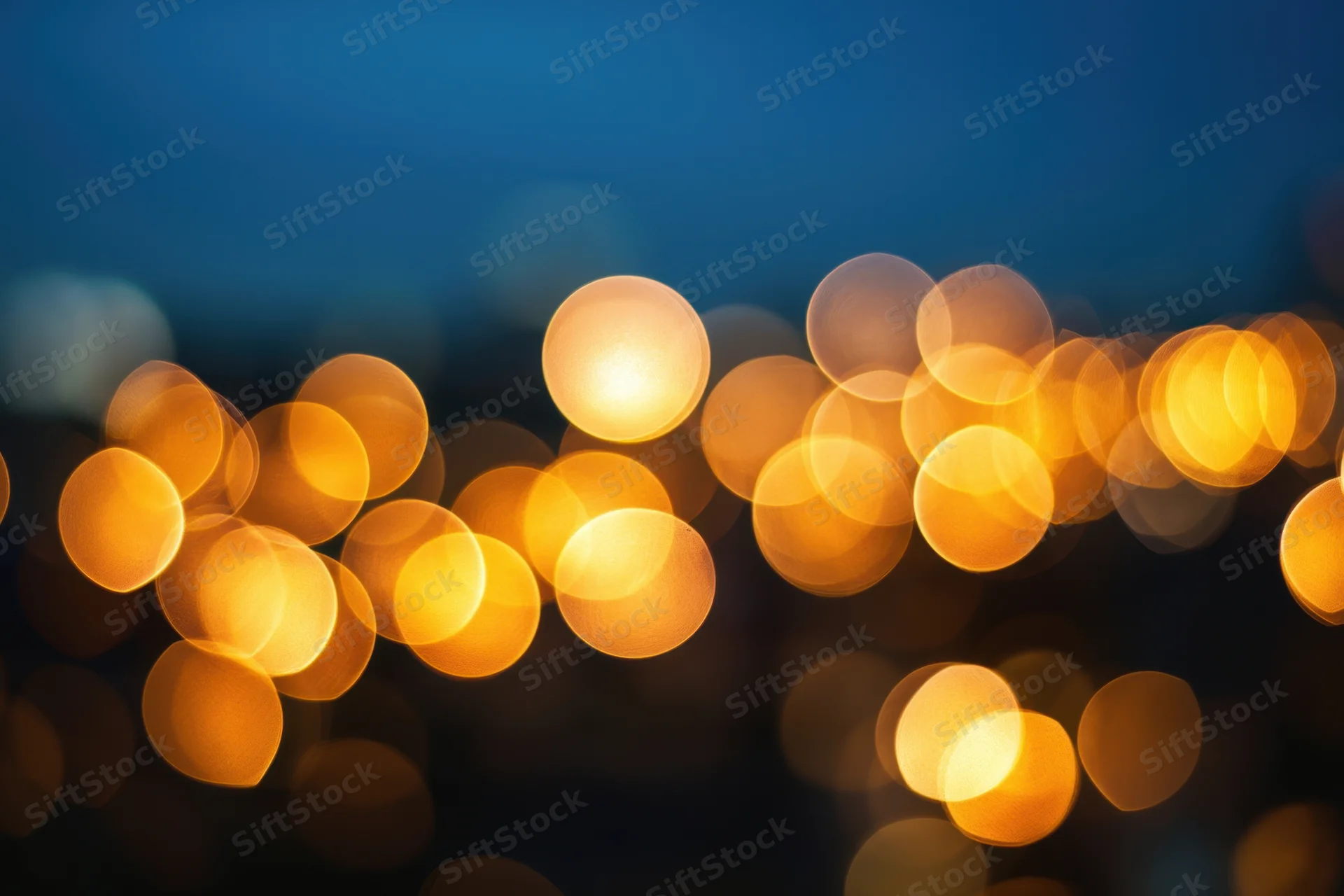 Warm golden bokeh lights scattered over a deep blue night background
