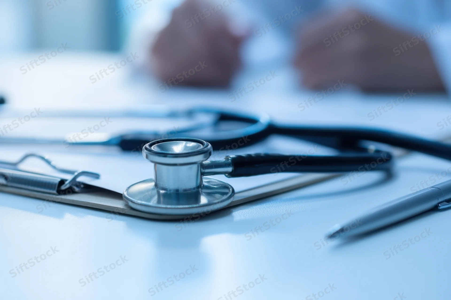 Stethoscope resting on clipboard with pen on desk during medical consultation