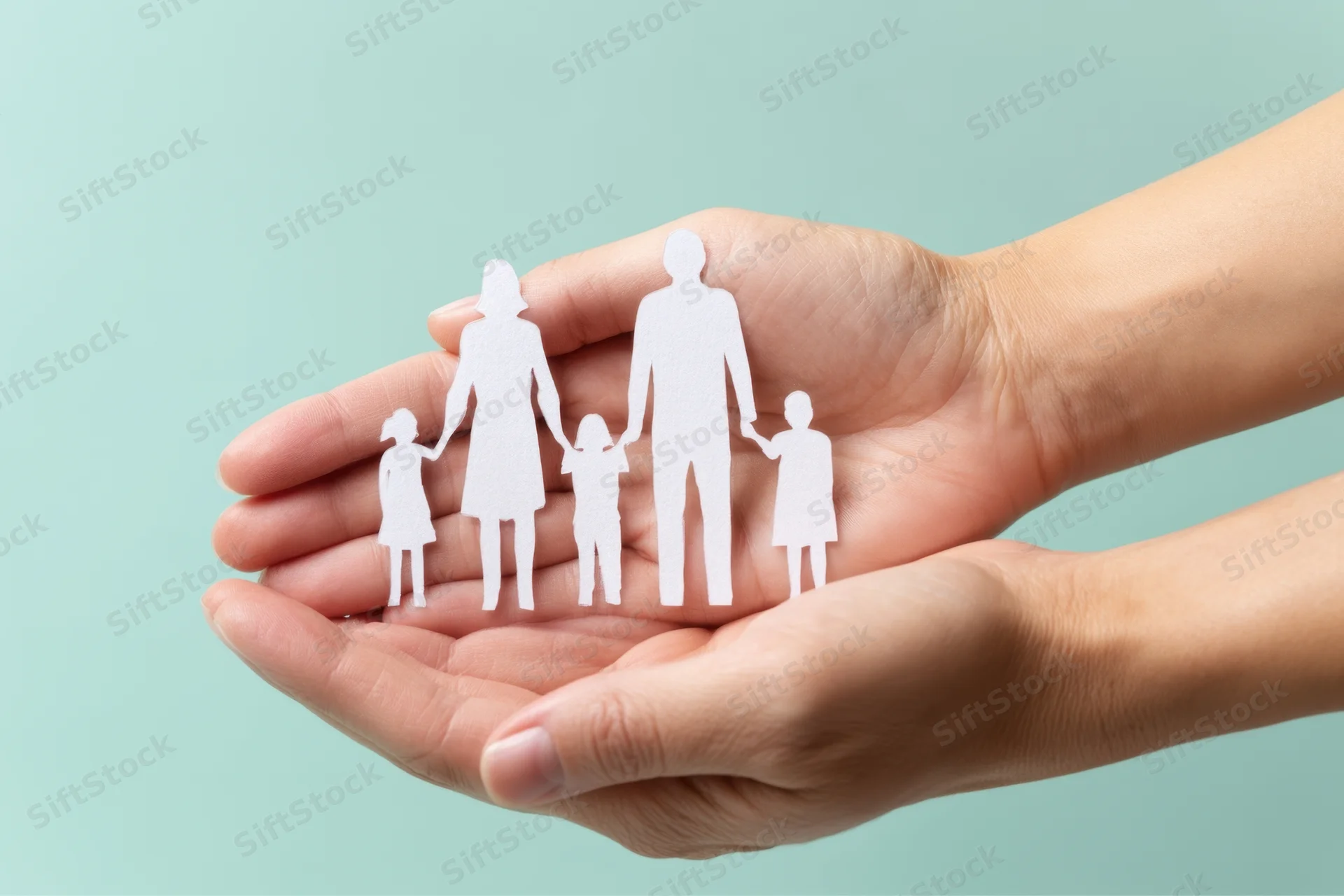 Hands cupping a paper family cutout against a light blue background