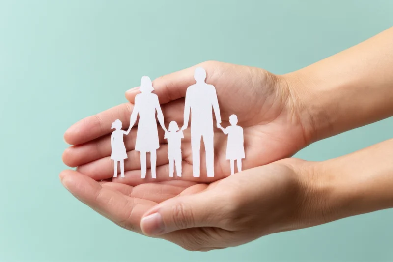 Hands cupping a paper family cutout against a light blue background