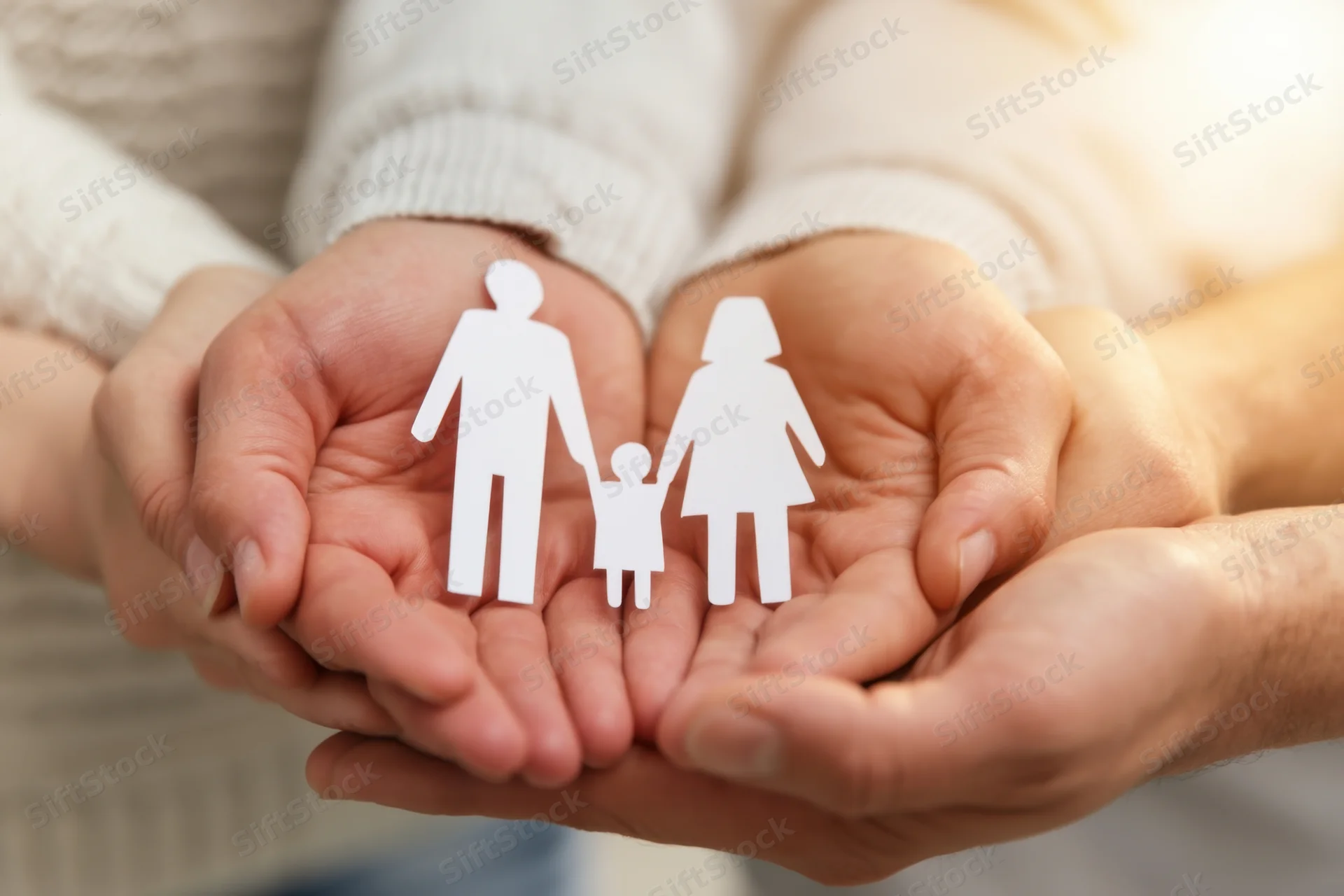 Hands cupping a white paper family cutout in a gesture of care and protection