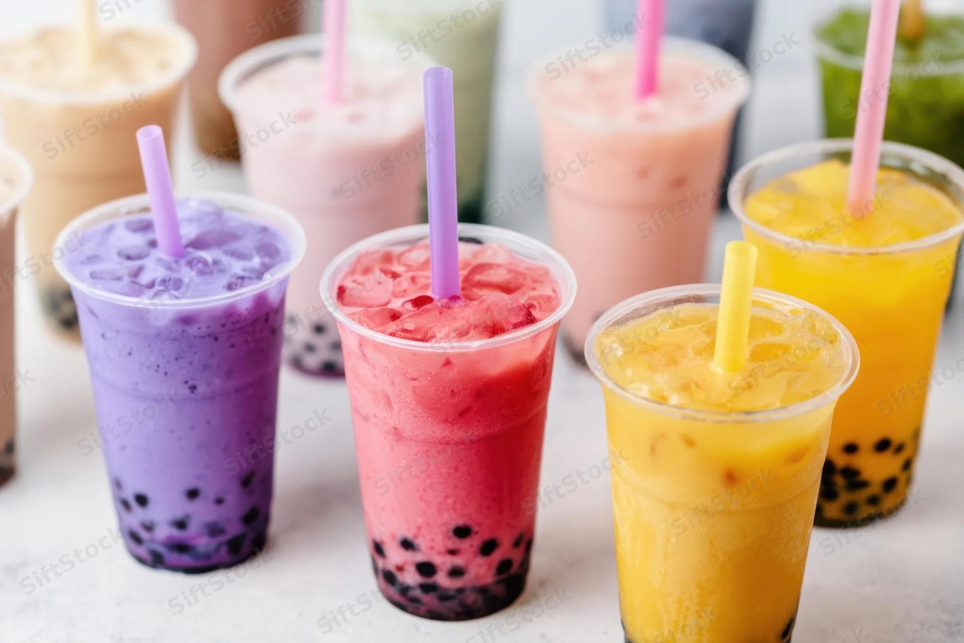 Colorful bubble tea drinks in clear cups with straws arranged on a light surface