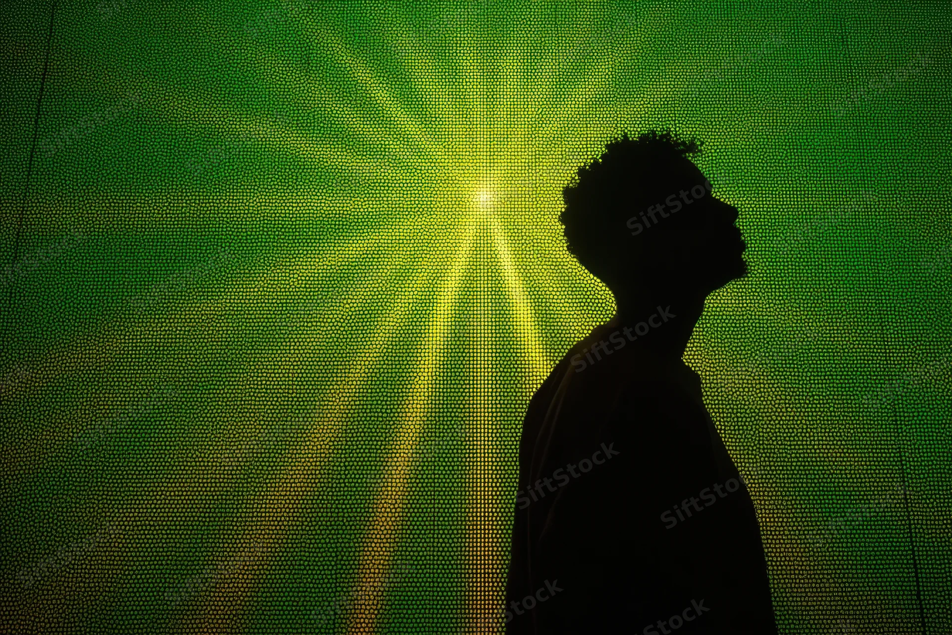 Silhouette of a man in profile against a glowing green digital screen