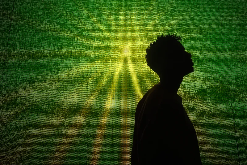 Silhouette of a man in profile against a glowing green digital screen