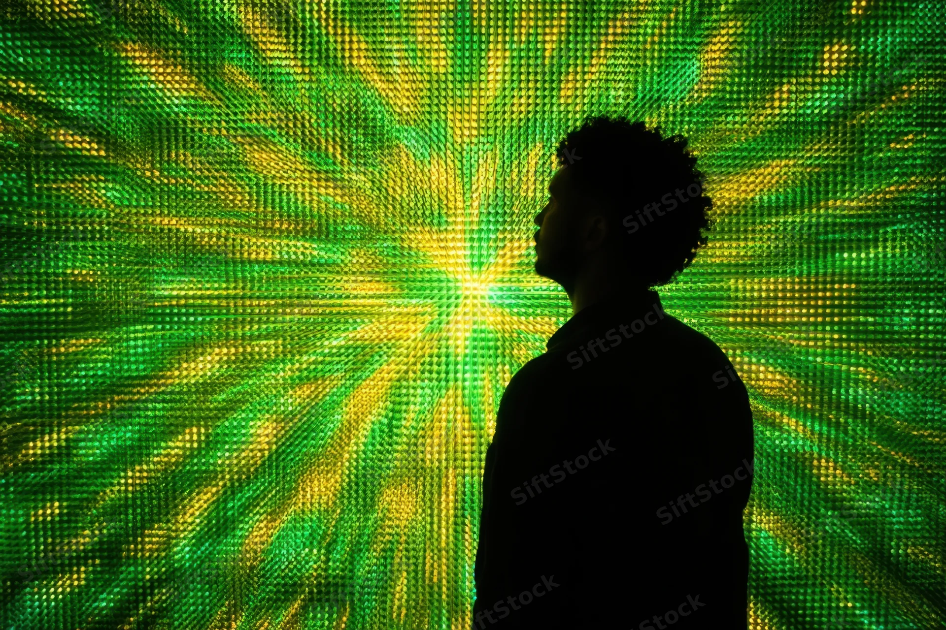 Silhouette of a man in profile standing before a glowing green and yellow digital display