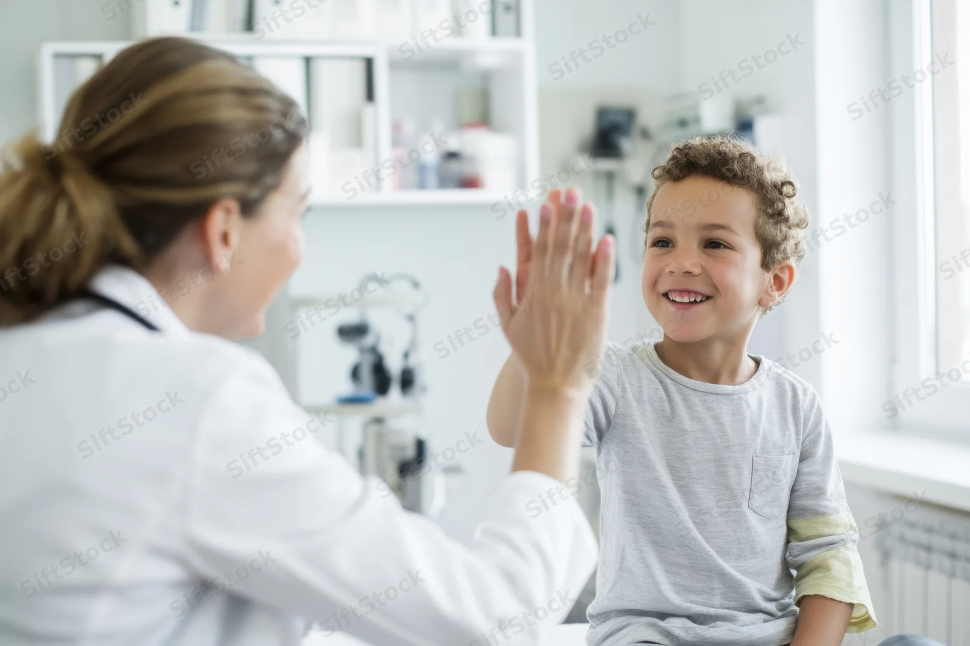 Child smiling and high-fiving doctor in a clinic office