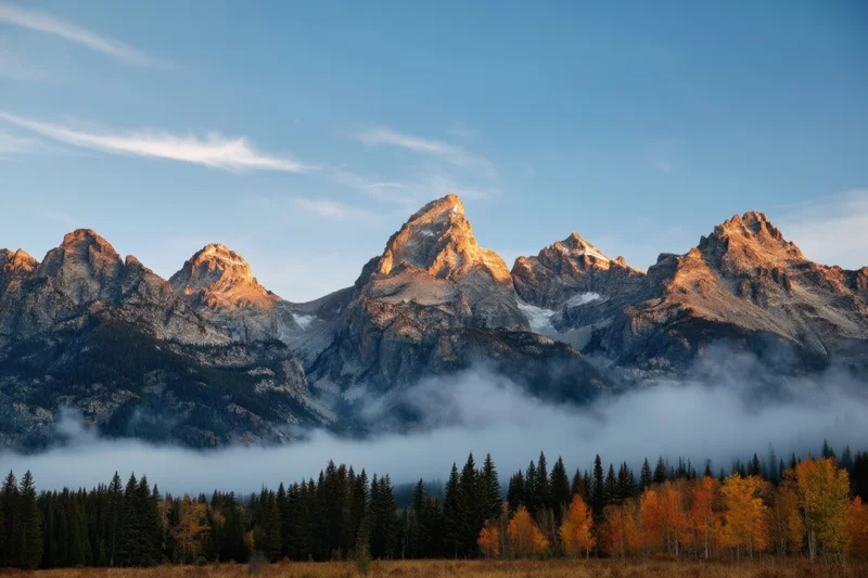 Jagged granite mountain peaks rising above misty valley with autumn forest below