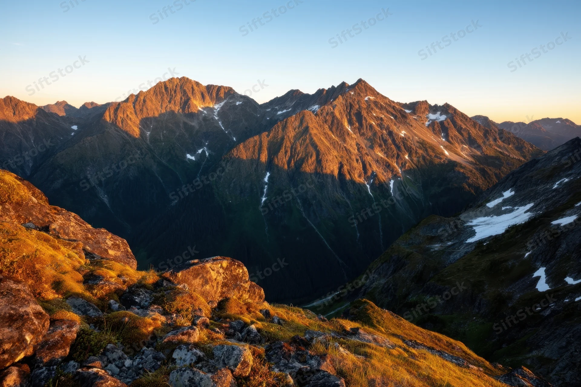 Rugged alpine peaks bathed in golden sunset light overlooking a deep valley