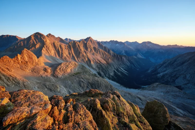 Rugged alpine peaks at sunset viewed from a high ridge overlooking a deep valley