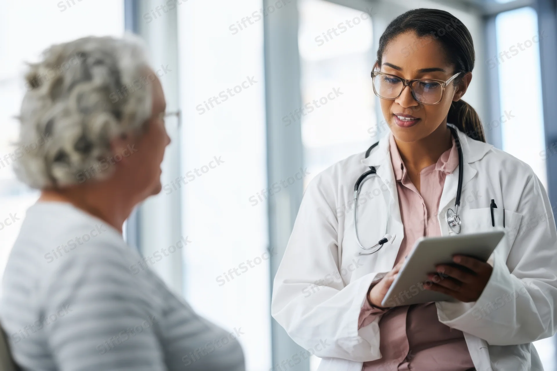 Female doctor showing tablet to senior patient during consultation in clinic