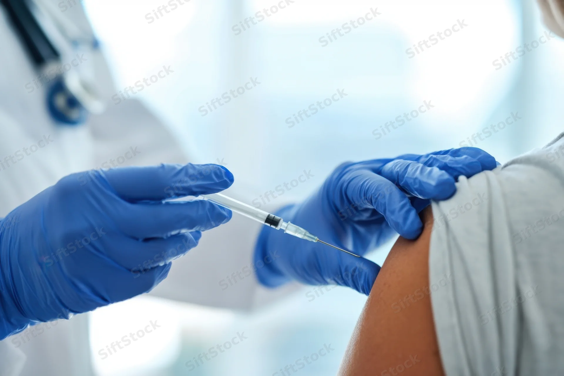 Healthcare worker administering injection into patient's shoulder in clinical setting