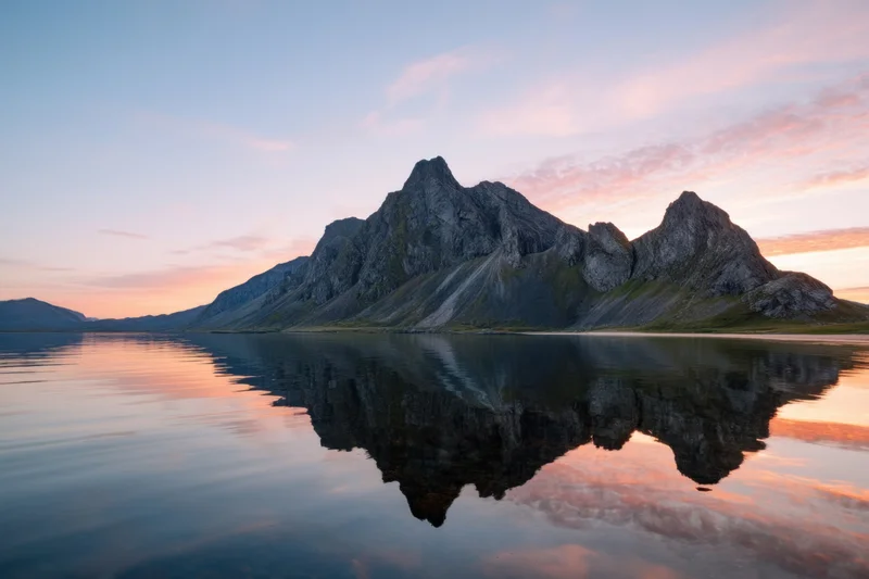 Jagged mountain island reflected in calm sea at sunset