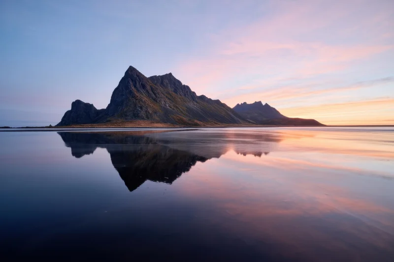Jagged mountain island reflected in still sea at twilight