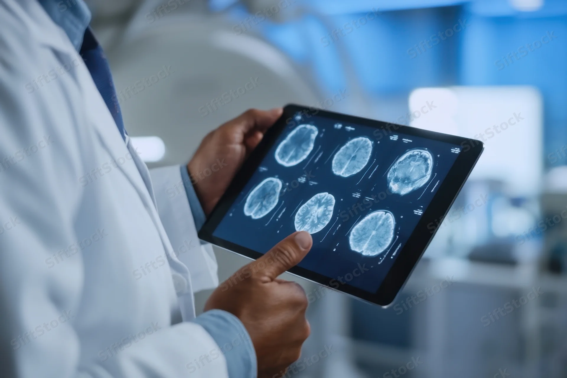 Doctor in white lab coat holding tablet with brain MRI scans, pointing at image in hospital setting